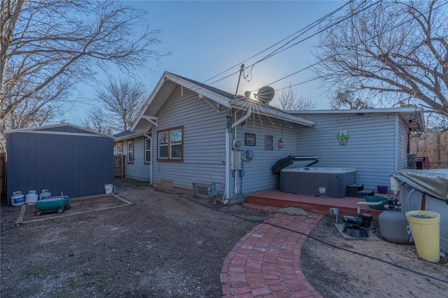 rear view of property with cooling unit, an outdoor structure, fence, a shed, and a hot tub