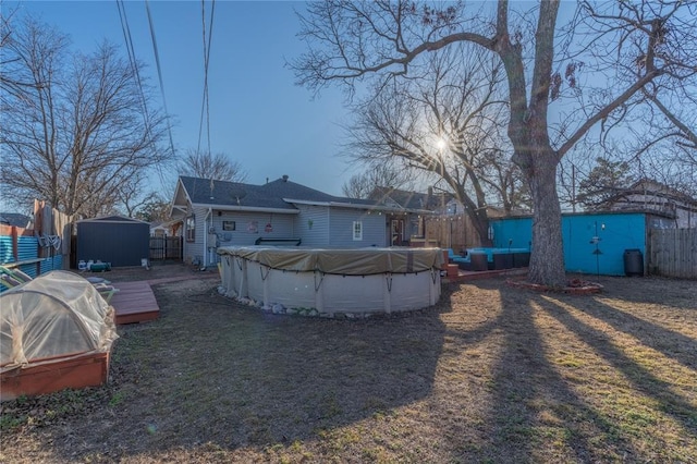 rear view of property featuring a shed, a fenced in pool, a fenced backyard, and an outdoor structure