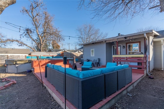 exterior space featuring outdoor lounge area, fence, a wooden deck, and a covered pool