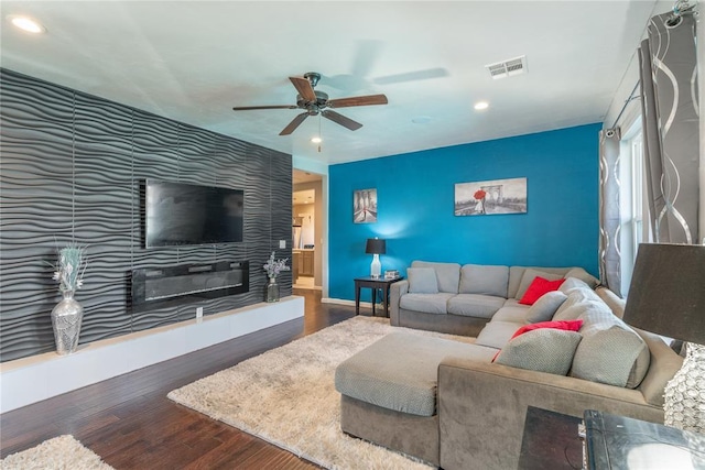 living room featuring an accent wall, recessed lighting, visible vents, and wood finished floors