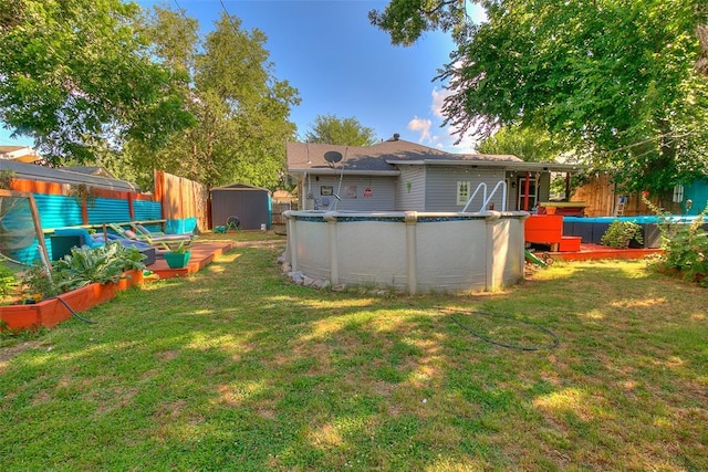 view of yard with an outbuilding, an outdoor pool, fence, and a storage shed