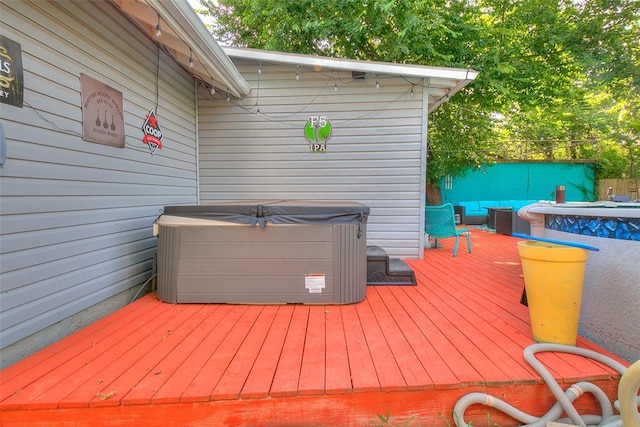 wooden deck with a hot tub and fence