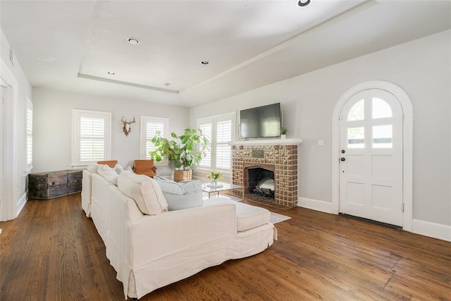 living room featuring a raised ceiling, wood finished floors, and baseboards