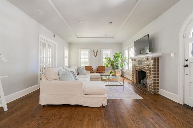 living room with a tray ceiling, baseboards, and wood finished floors