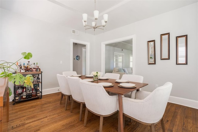 dining space with an inviting chandelier, wood finished floors, visible vents, and baseboards