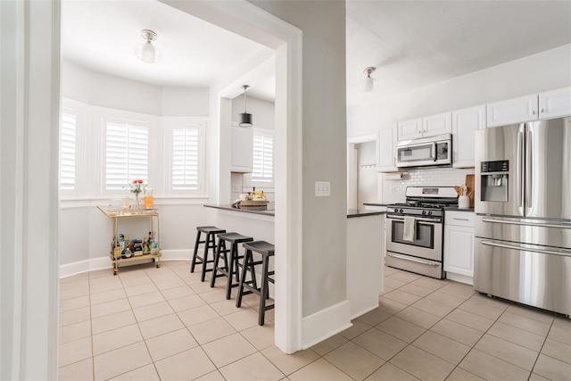 kitchen featuring light tile patterned floors, stainless steel appliances, dark countertops, and white cabinets