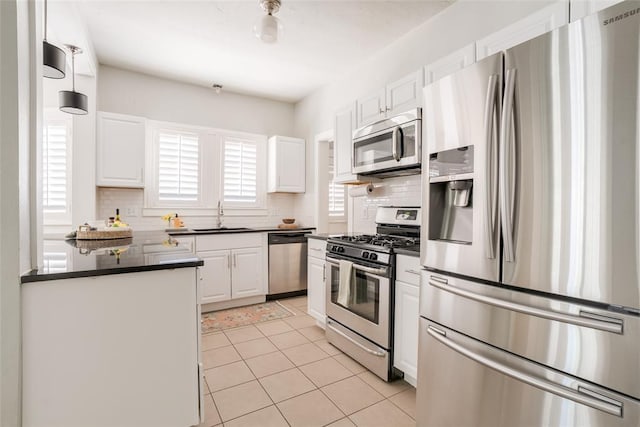 kitchen featuring dark countertops, white cabinets, appliances with stainless steel finishes, and a sink