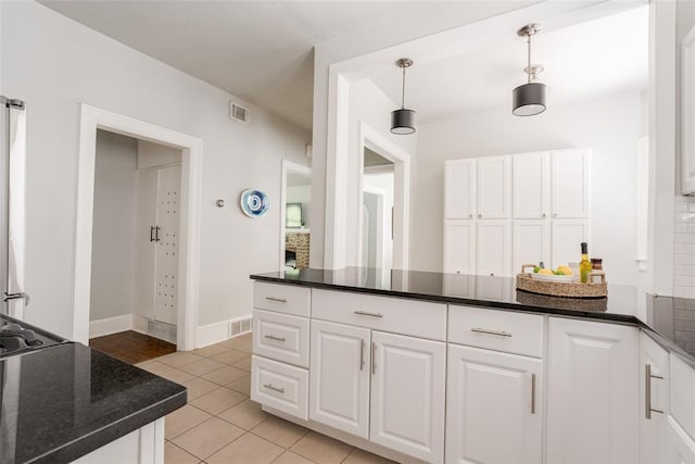 kitchen featuring light tile patterned floors, visible vents, a peninsula, pendant lighting, and white cabinetry