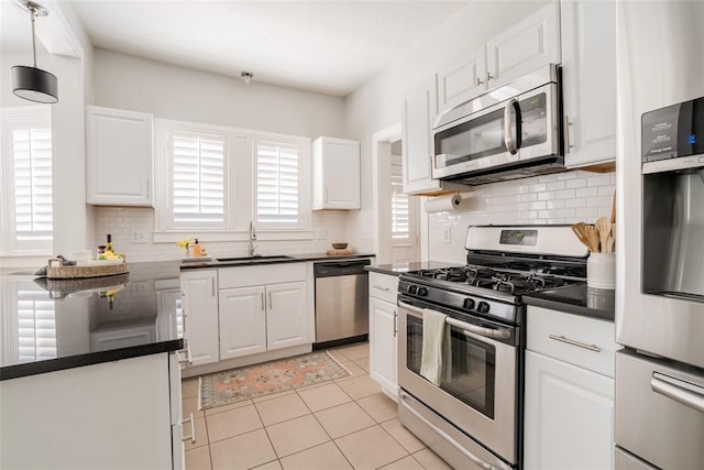 kitchen featuring dark countertops, appliances with stainless steel finishes, white cabinetry, and a sink