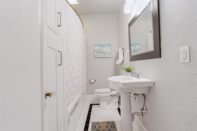 bathroom featuring baseboards, a sink, tile patterned flooring, curtained shower, and toilet