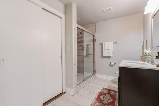 bathroom with visible vents, toilet, a stall shower, baseboards, and vanity