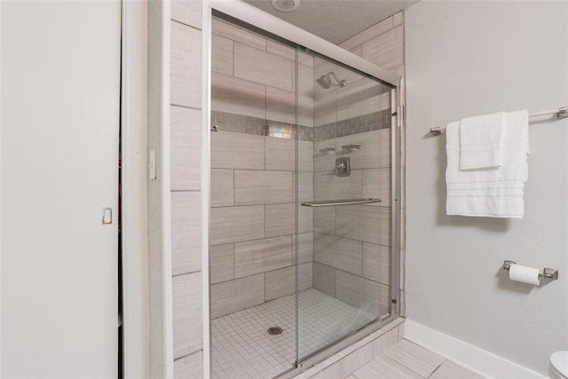 full bath featuring tile patterned floors, baseboards, and a stall shower