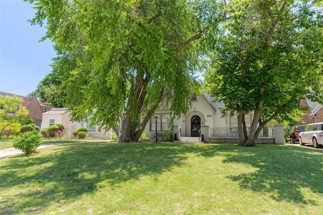 view of property hidden behind natural elements featuring a front lawn and stucco siding