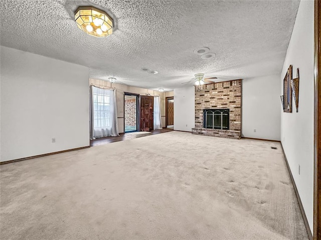 unfurnished living room featuring ceiling fan, a brick fireplace, light colored carpet, and a textured ceiling