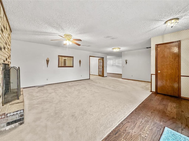 unfurnished living room with hardwood / wood-style floors, a fireplace, a textured ceiling, and ceiling fan