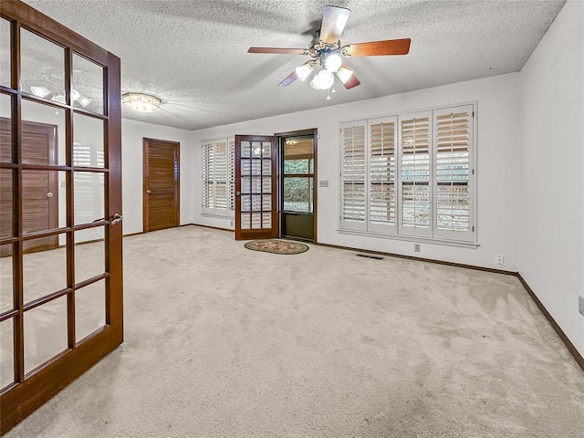 carpeted empty room featuring ceiling fan and a textured ceiling