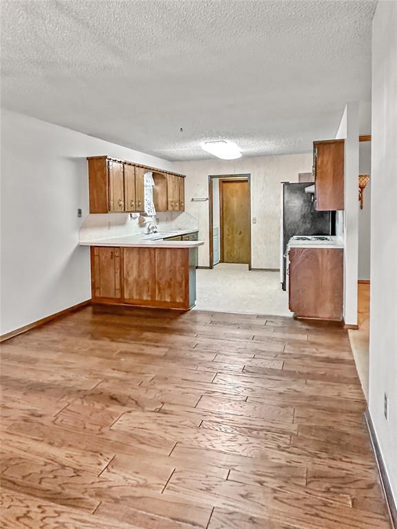 kitchen featuring light hardwood / wood-style floors, kitchen peninsula, and a textured ceiling