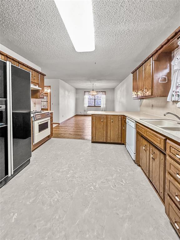 kitchen featuring sink, white appliances, and a textured ceiling