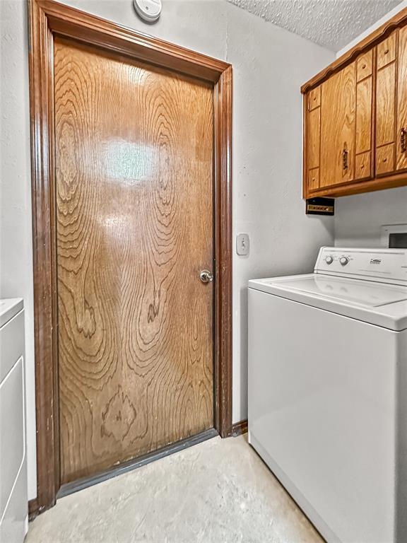 laundry room featuring cabinets, washer / clothes dryer, and a textured ceiling