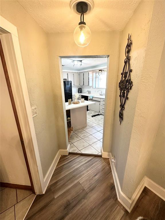 corridor with a textured ceiling and light wood-type flooring