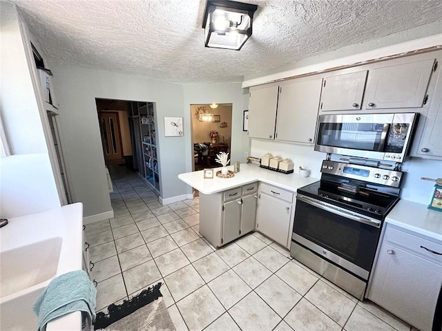 kitchen featuring stainless steel appliances, light tile patterned flooring, gray cabinetry, and kitchen peninsula