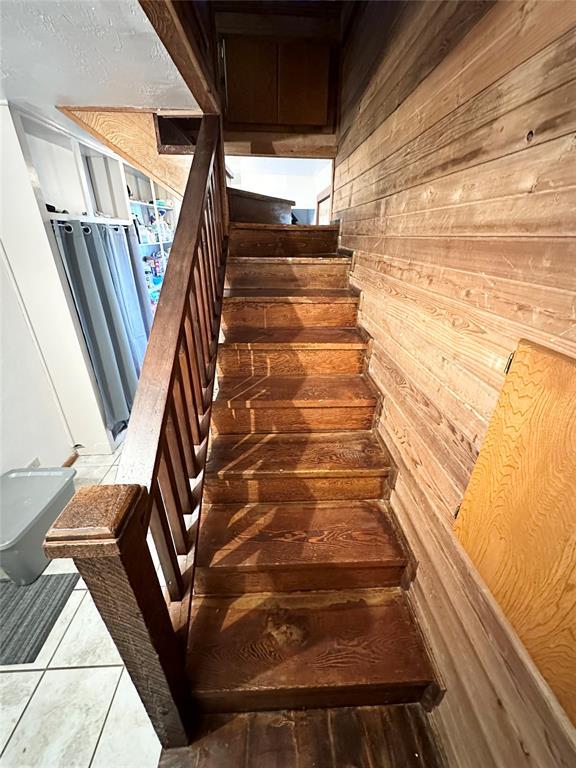 staircase with wooden walls and tile patterned flooring