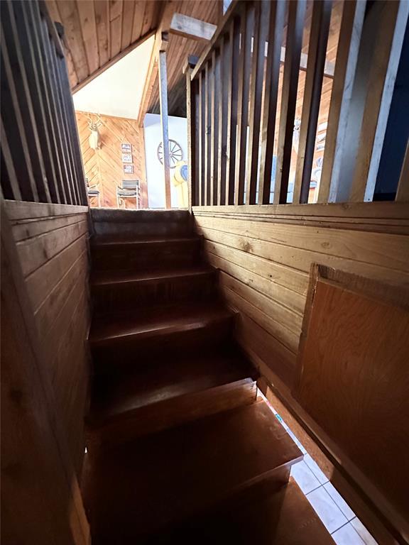 staircase featuring tile patterned floors and wood walls