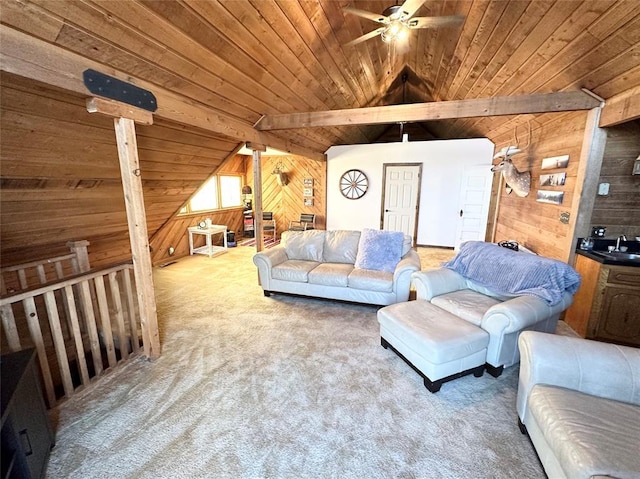 carpeted living room with wood walls, vaulted ceiling with beams, sink, ceiling fan, and wood ceiling