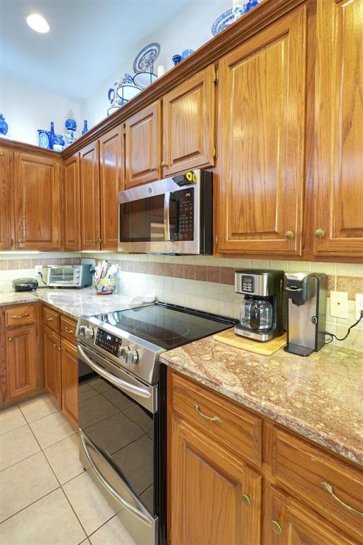 kitchen featuring stainless steel appliances, light tile patterned floors, and backsplash