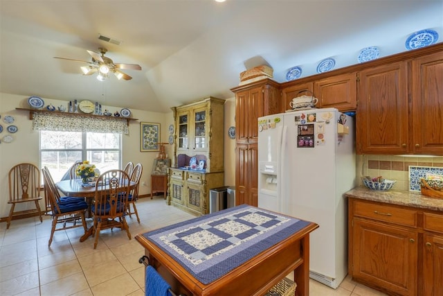 kitchen with lofted ceiling, decorative backsplash, white fridge with ice dispenser, light tile patterned floors, and ceiling fan