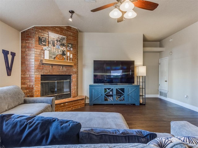 living room with ceiling fan, a fireplace, a textured ceiling, dark hardwood / wood-style flooring, and vaulted ceiling