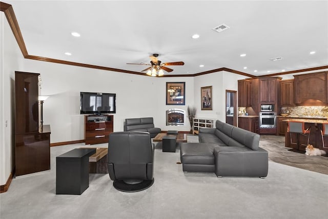 carpeted living room with ornamental molding and ceiling fan