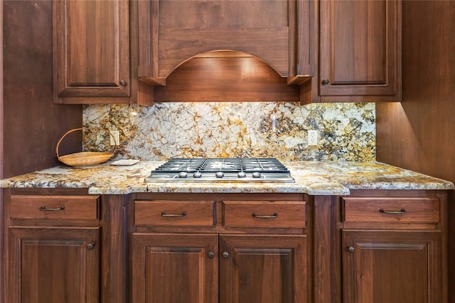 kitchen featuring tasteful backsplash, light stone countertops, and stainless steel gas cooktop