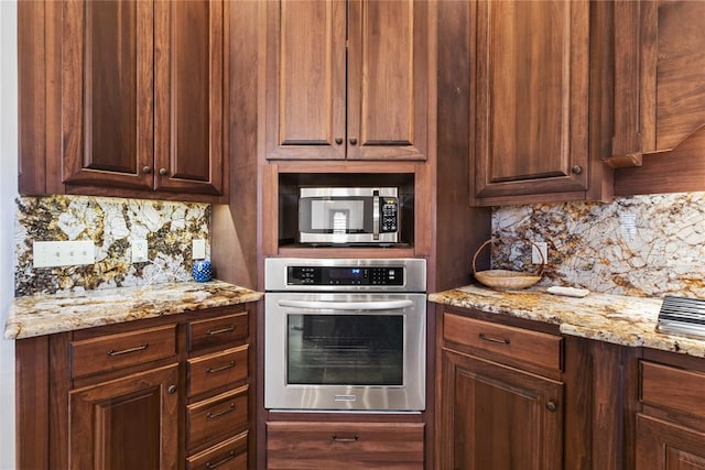 kitchen with stainless steel appliances, light stone counters, and decorative backsplash