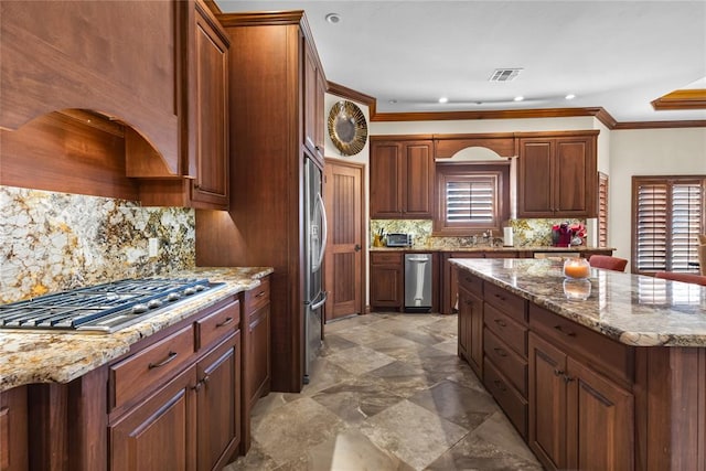 kitchen with tasteful backsplash, crown molding, appliances with stainless steel finishes, and plenty of natural light