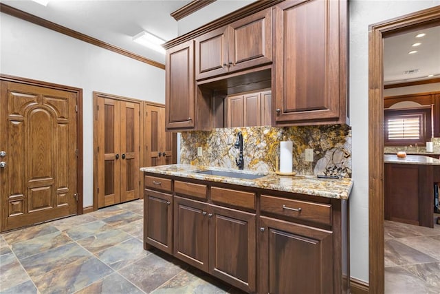 kitchen featuring dark brown cabinetry, sink, crown molding, light stone counters, and backsplash