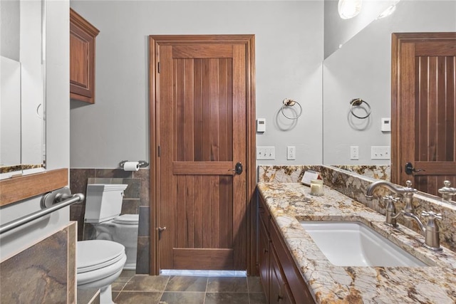 bathroom featuring vanity, toilet, and tile walls