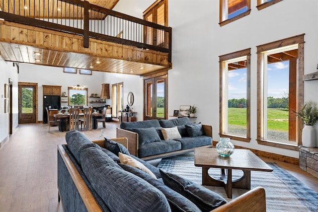 living room featuring wood ceiling, wood-type flooring, french doors, and a high ceiling