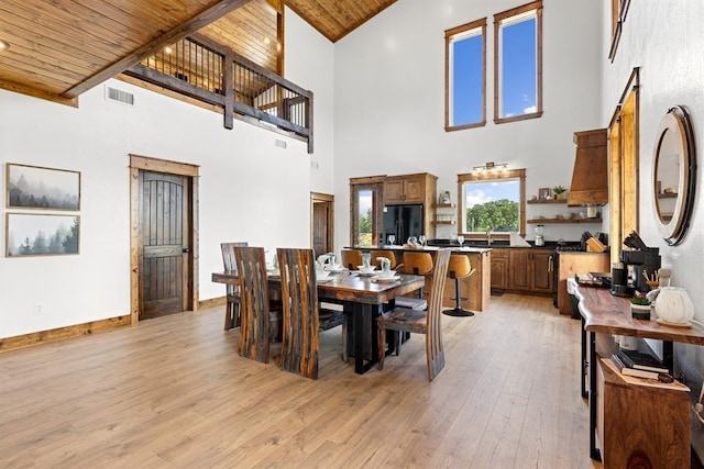 dining area featuring a towering ceiling, light hardwood / wood-style flooring, and wooden ceiling