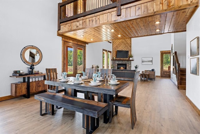 dining area with a fireplace, wooden ceiling, light hardwood / wood-style floors, and french doors