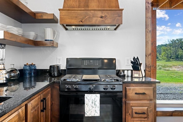 kitchen featuring custom exhaust hood, gas stove, and dark stone countertops