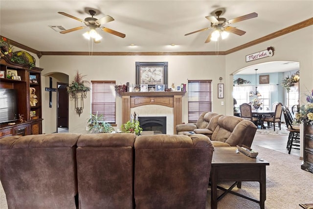 carpeted living room with a high end fireplace, arched walkways, and a healthy amount of sunlight