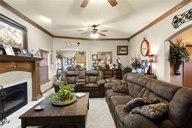 living room featuring ornamental molding, arched walkways, light carpet, and a glass covered fireplace