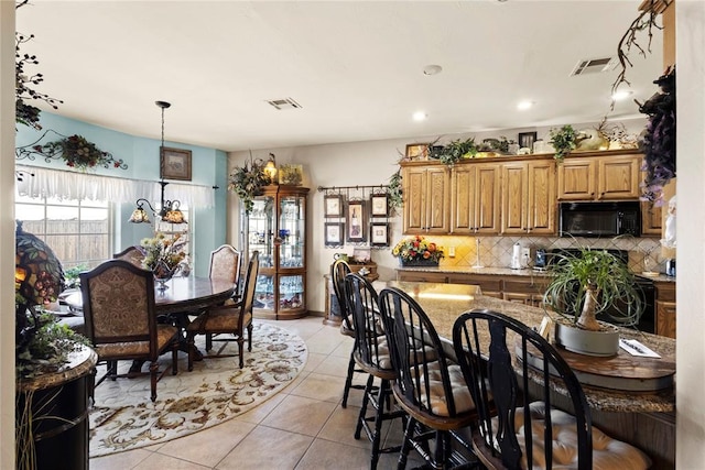 kitchen featuring black microwave, light tile patterned floors, backsplash, and visible vents