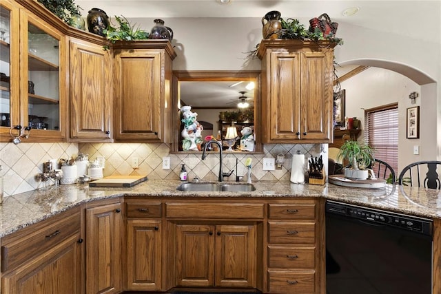 kitchen featuring arched walkways, dishwasher, glass insert cabinets, backsplash, and a sink