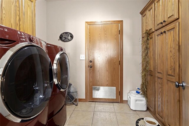 laundry area featuring cabinet space, light tile patterned floors, baseboards, and washer and clothes dryer