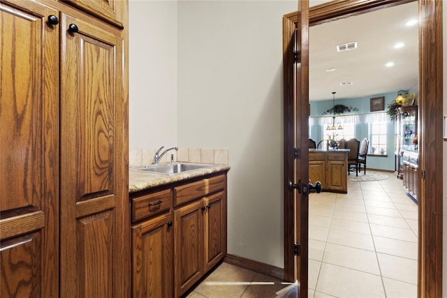 interior space featuring brown cabinets, light countertops, visible vents, light tile patterned flooring, and a sink