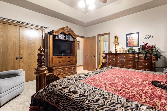 carpeted bedroom with a tray ceiling and a ceiling fan