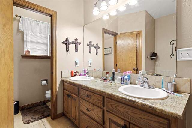 bathroom with tile patterned flooring, a sink, toilet, and double vanity