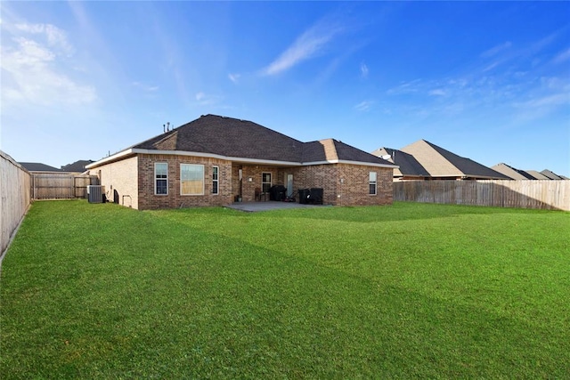 rear view of house with brick siding, a patio, a lawn, central AC unit, and a fenced backyard